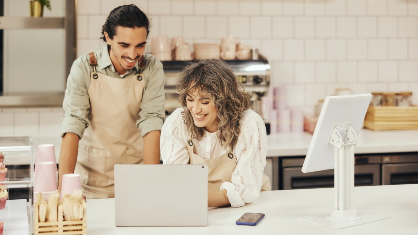 Two people work on a laptop while at work at a cafe.