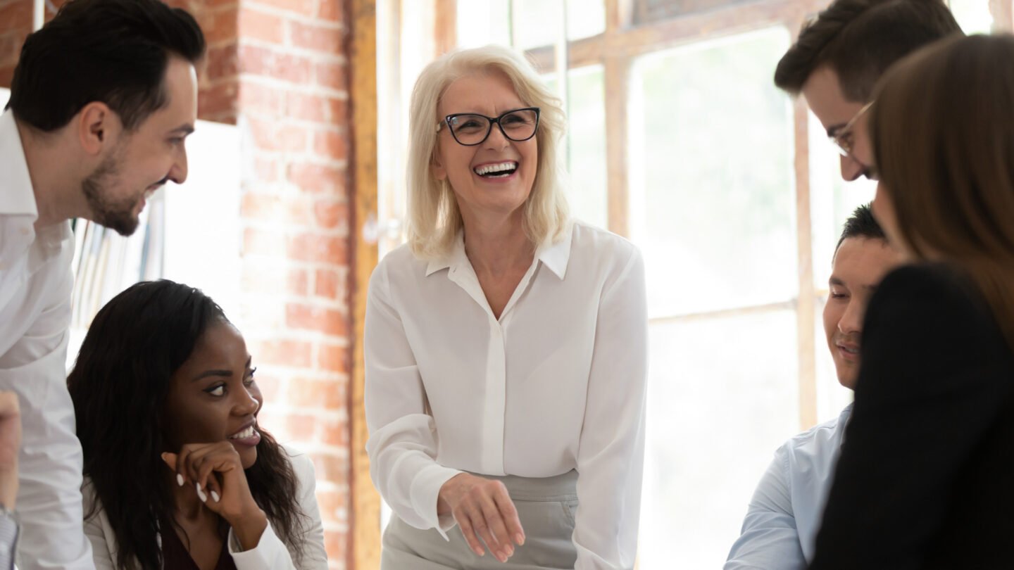 A group of people laugh during a meeting in a modern office