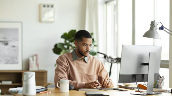 Homem a trabalhar em frente ao seu computador.