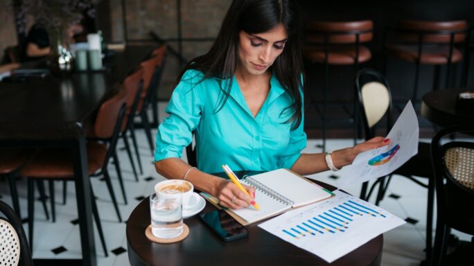 Uma jovem mulher a trabalhar, revisando documentos em sua mesa.