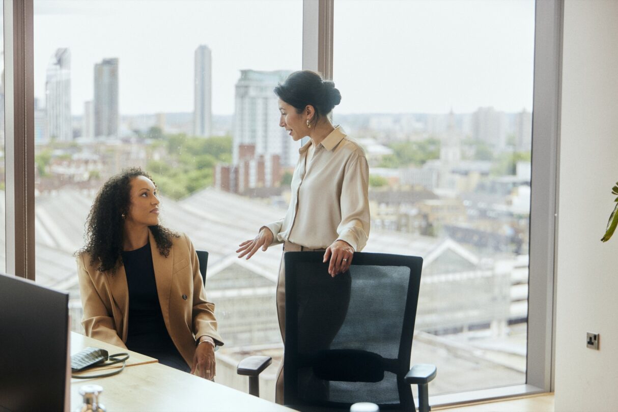 Duas colegas de trabalho conversando no escritório.